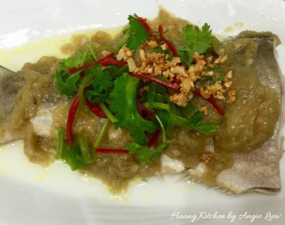 Top the fish with the cooked ginger paste and sprinkle with fried garlic and garlic oil. Garnish with green coriander leaves, spring onion and red chili.