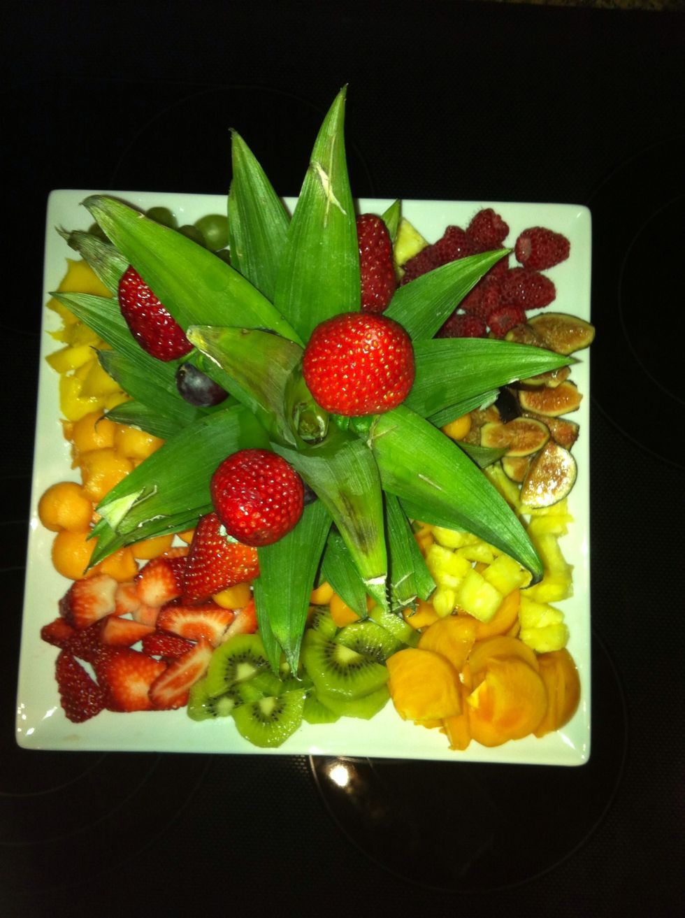 Top view... This plate contains strawberries, kiwi, persimmon, pineapple, figs, green and red grapes, raspberries, mango and cantaloupe. Left over fruits were mixed and stored as a fruit salad.