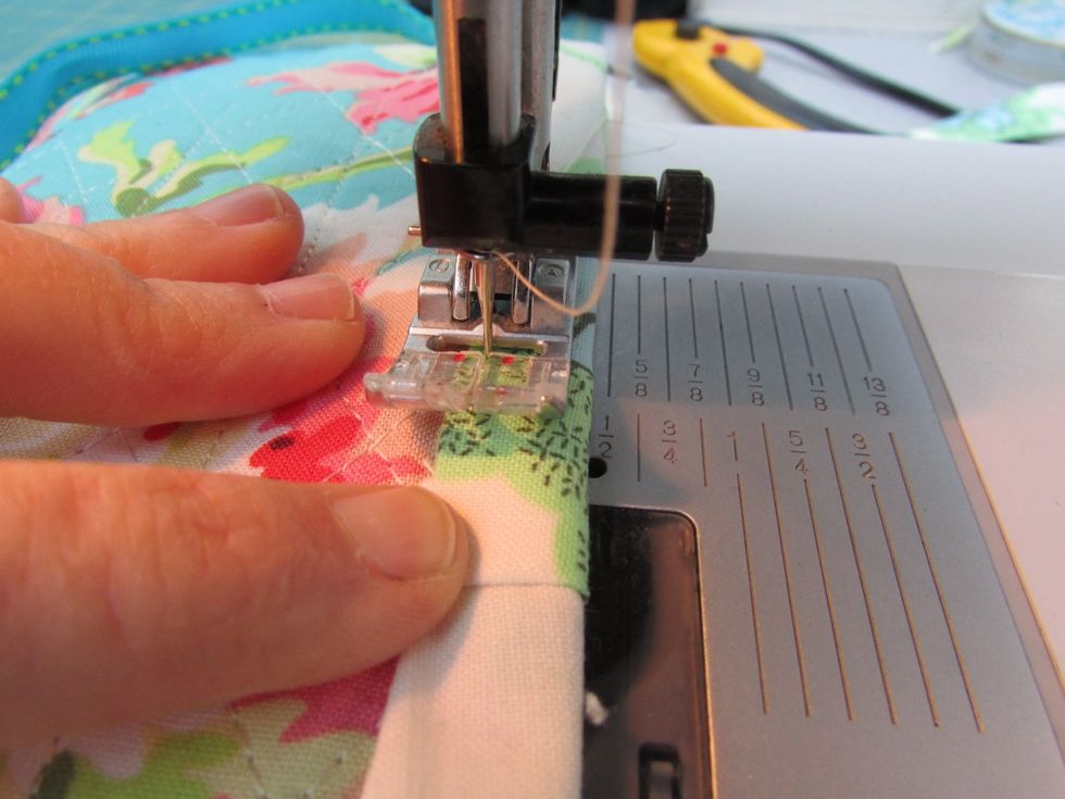 Topstitch the edge trim down on the outside, covering the stitch line, just enough to secure it down. Stitch all the way around, pivoting at corners.