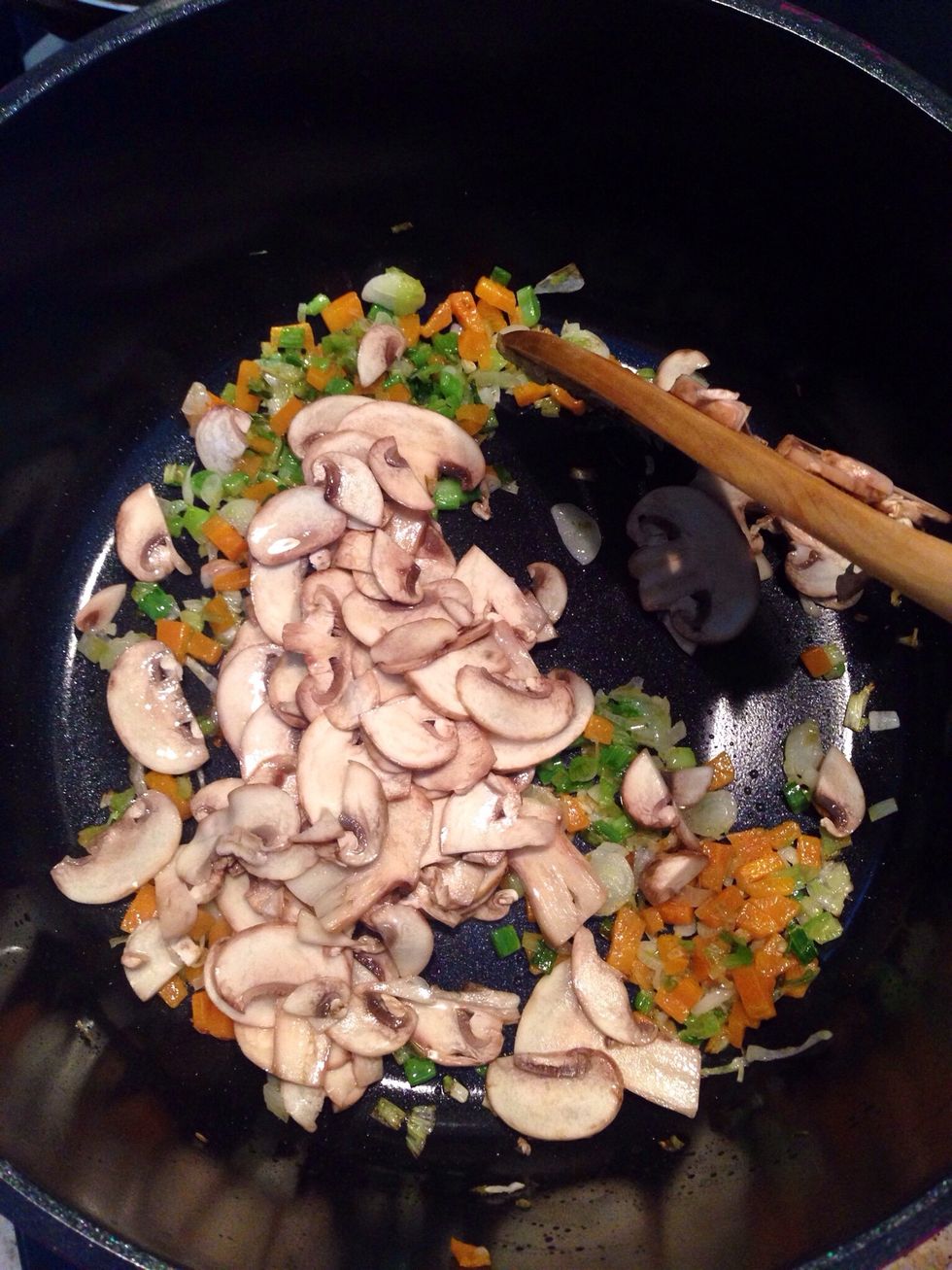 Toss in the sliced mushrooms and saut\u00e9 . Add half of the pounded broth cube and fry