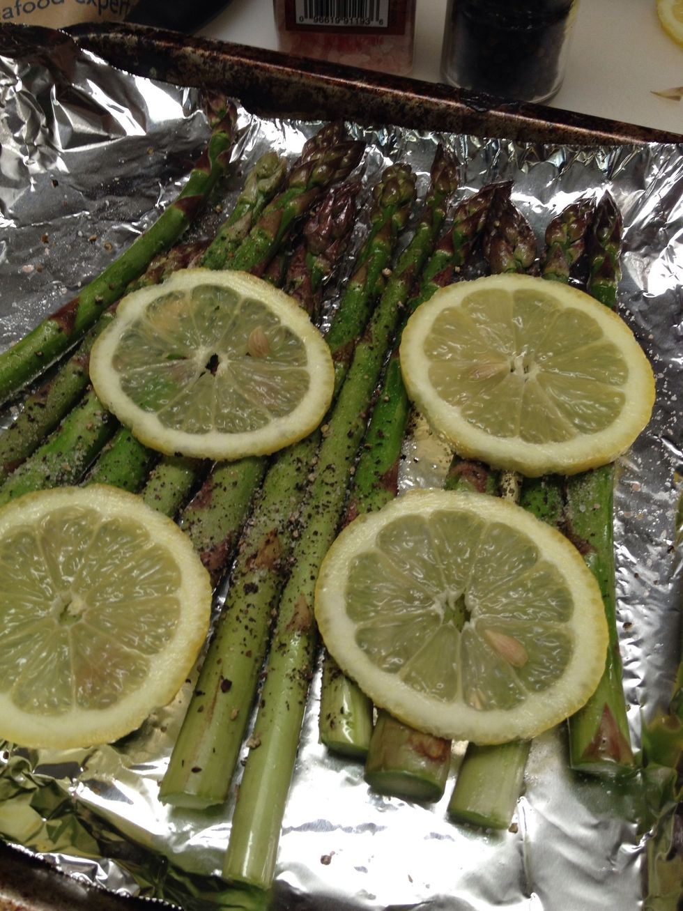 Toss the asparagus in olive; just enough to coat. Then sprinkle with salt and pepper and place lemon slices on top.   Roast in 400degree F. oven. About 5-6 minutes, if you like it a little browned.