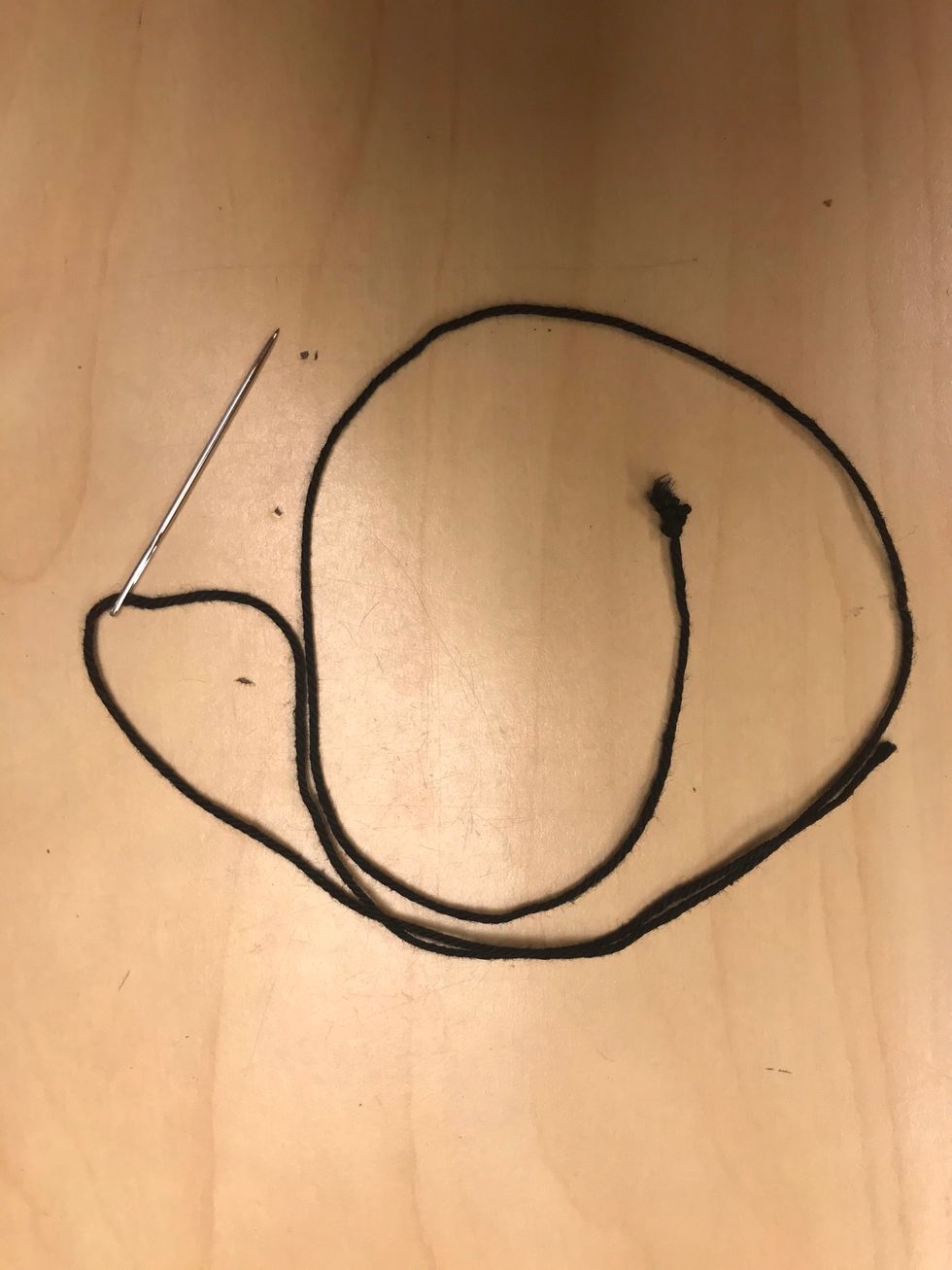Tr\u00e4 en spetsig broderin\u00e5l med bomullsgarn och g\u00f6r en syknut i slutet p\u00e5 tr\u00e5den.