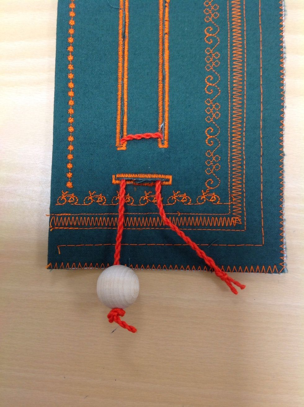 Tr\u00e4 i kulorna i snodden. G\u00f6r flera knutar p\u00e5 varandra s\u00e5 att inte kulan kan \u00e5ka av.