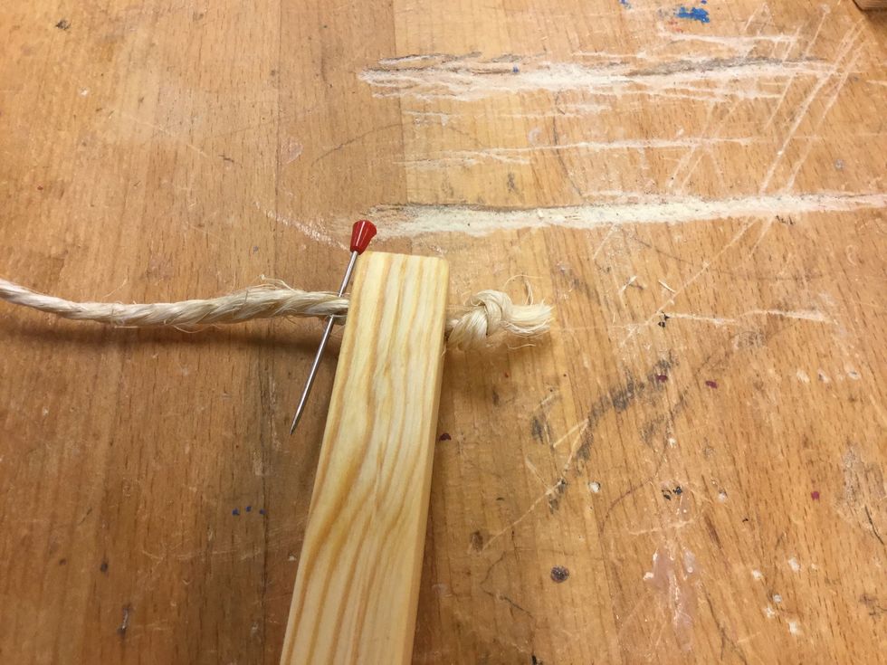 Tr\u00e4 igenom sn\u00f6ret genom en av pinnarna. F\u00f6r att f\u00e5 n\u00e4sta knut riktigt n\u00e4ra pinnen ska vi anv\u00e4nda en n\u00e5l till hj\u00e4lp. Stick igenom n\u00e5len n\u00e4ra pinnen.