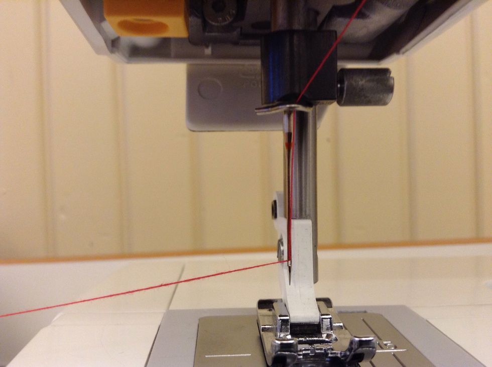 Tr\u00e4 tr\u00e5den genom n\u00e5ls\u00f6gat. Det kan g\u00e5 l\u00e4ttare om du f\u00f6rst klipper av tr\u00e5den.