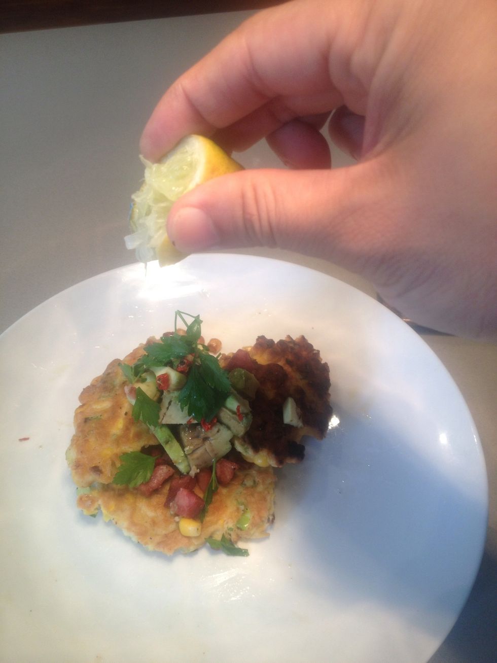 Transfer fritters to a plate. Top with diced avocado, chilli, parsley, diced ham and a squeeze of lemon. Drizzle olive oil on top.