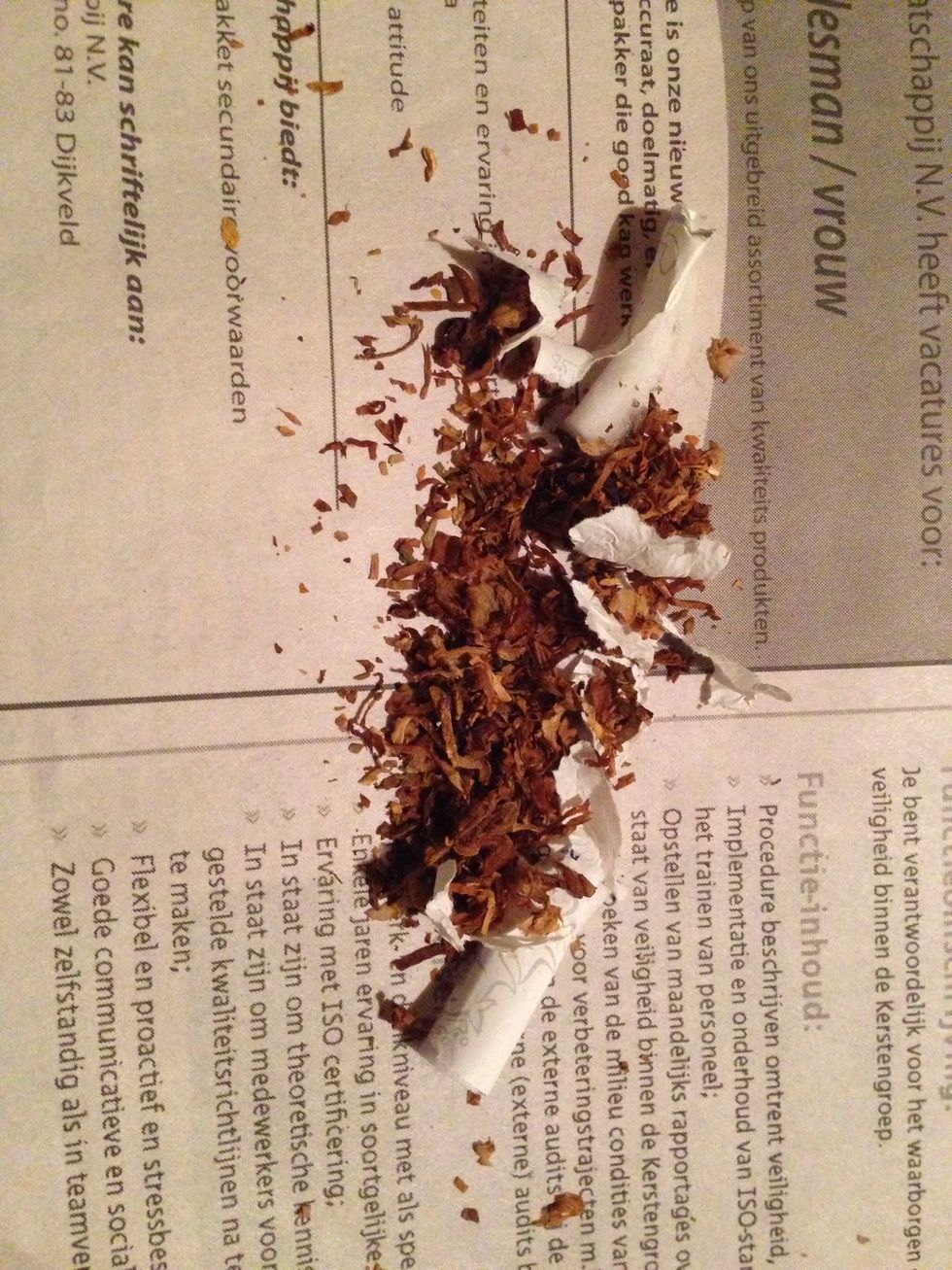 Transfer the broken up cigarette unto the newspaper.
