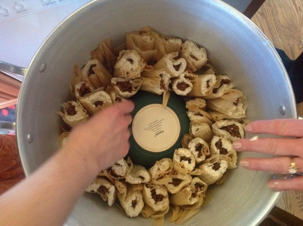 Tuck raw tamales open ends up into steamer.