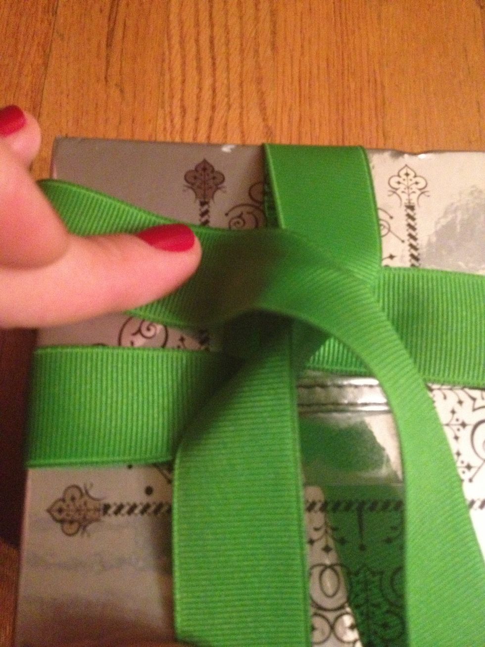 Tuck the tail end (the one you just cut) into the corner where the start end of the ribbon is coming out of.
