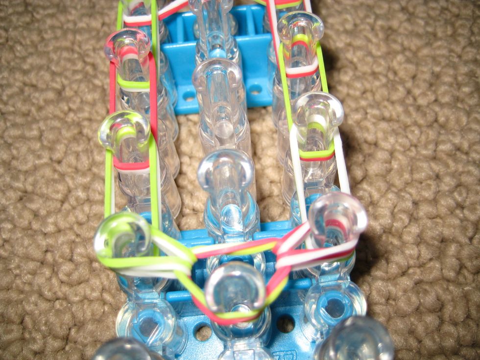 Turn around. Reach under cap band, grab top 2 bands and pull to the next peg. Do to other side too.