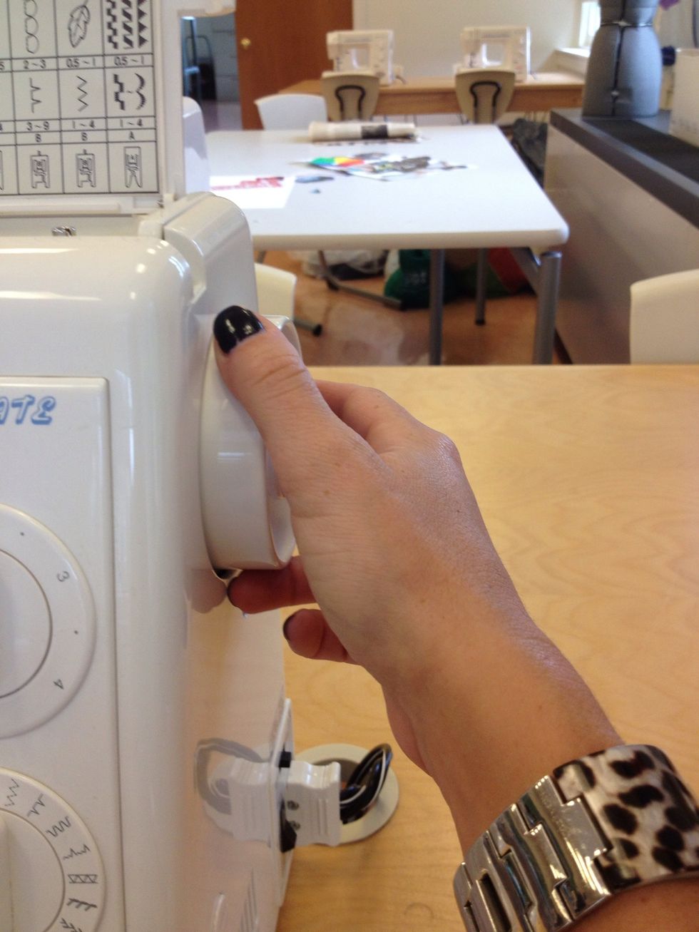 Turn hand wheel towards you until needle going down and comes back up.