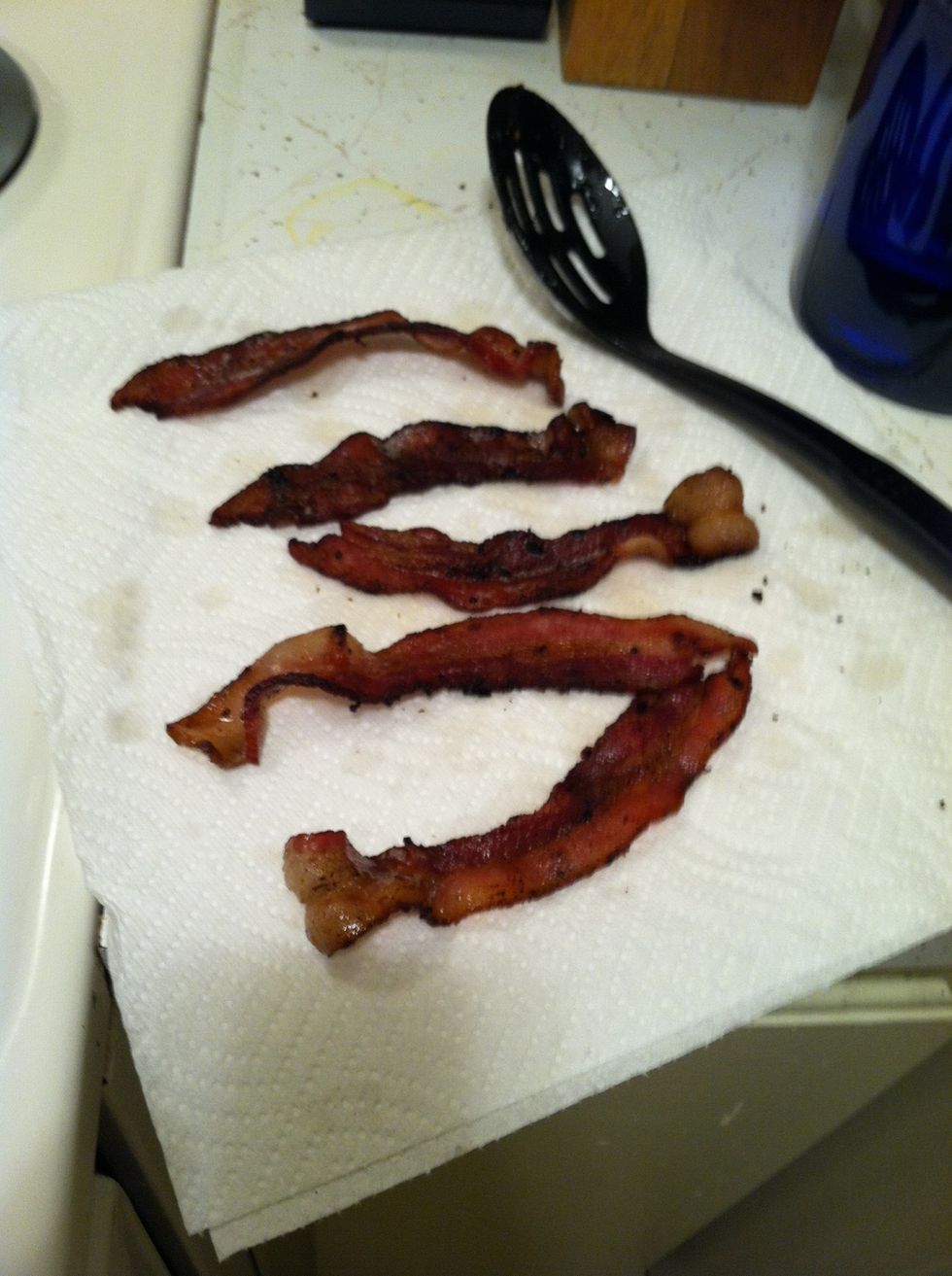 Turn off all heat on stove. Using a slotted spoon or tongs, move bacon from the pan onto a few paper towels.     Allow bacon to drain on paper towels (I.e.,, let the paper towels soak up the grease.)