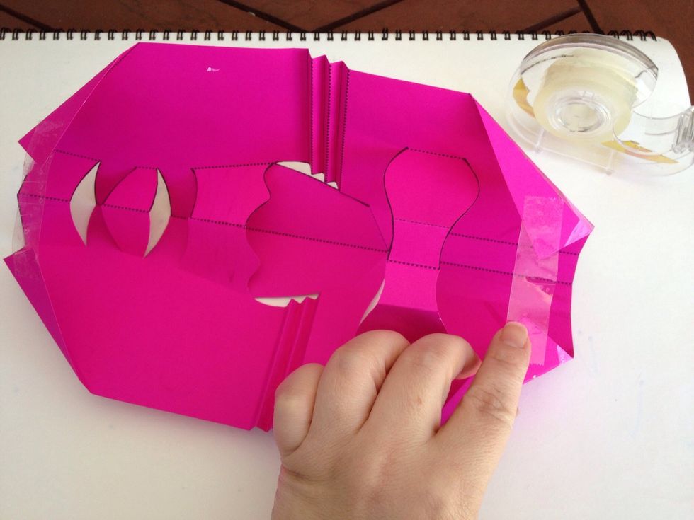 Turn over and tape the top and bottom corners together. The length of tape will determine the shape of the mask. You can also attach it to a piece of backing card.