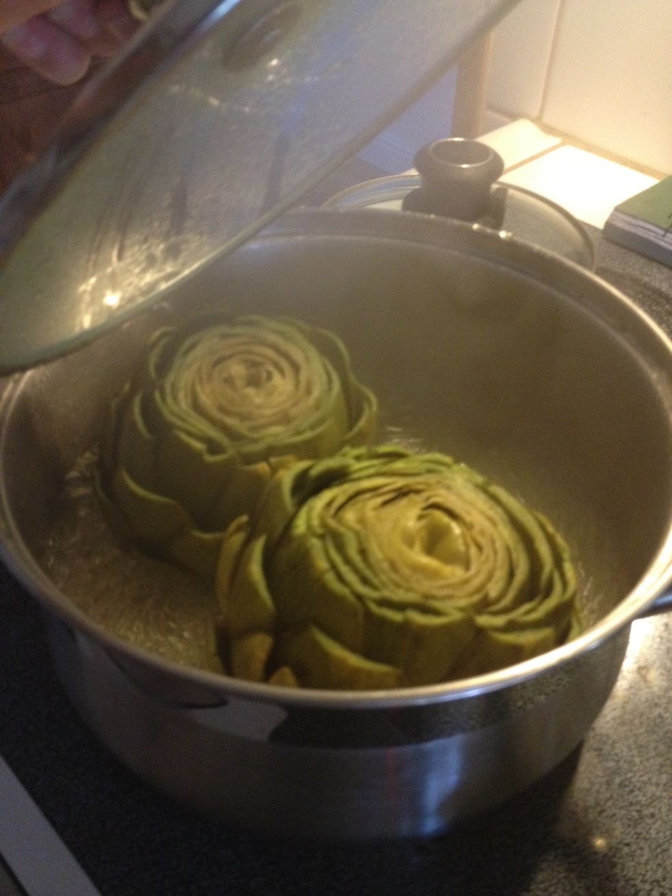 Turn right side up half way through and check that water level does not boil dry. Artichokes will be done when outside leaves pull off gently or center releases easily from fork.