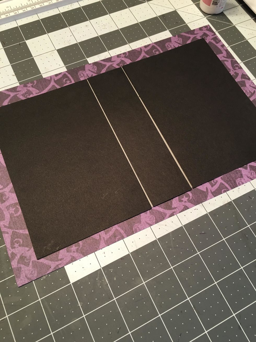 Turn the cardstock cover over with the adhesive side down and attach to the back side of the patterned paper, centered with about 3/4" - 1" around all 4 sides.