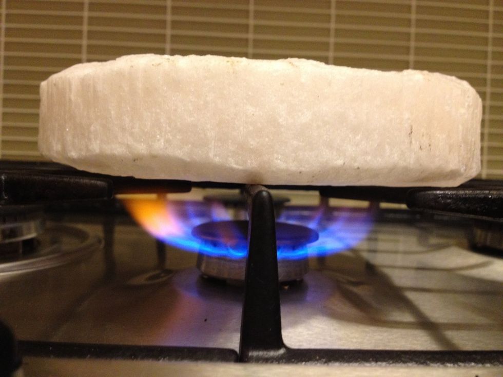 Turn the heat up to high. The salt block is hot enough when it is too hot to hold your hand 2 inches above it, and/or when a piece of meat sizzles like crazy when you drop it on the salt block.