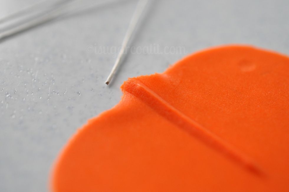 Turn the petal over. Cut four 26 gauge floral wires into thirds and lightly dampen one end with edible glue.