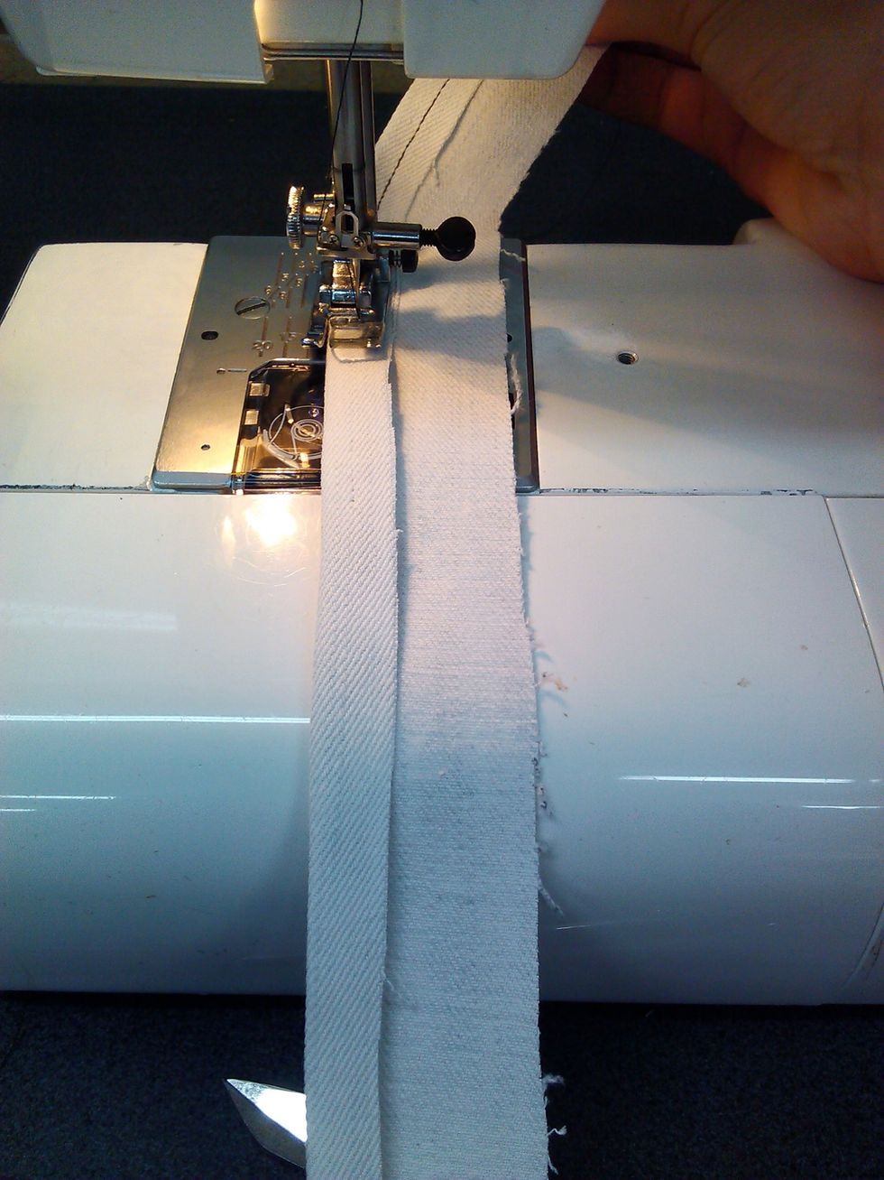 Turn the strap over an iron the strap so that both sides meet in the middle and sew along the sides