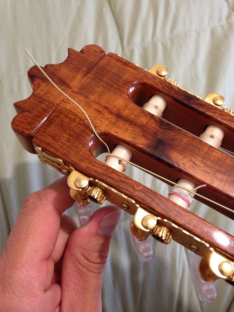 Turn the tuning peg, keeping an eye on the string, so it doesn't get untied.