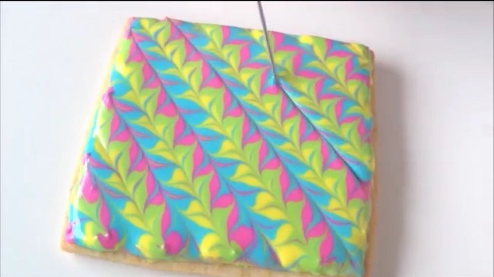 Turn your cookie 180 degrees and drag your toothpick through the middle of the stripes you just drew.