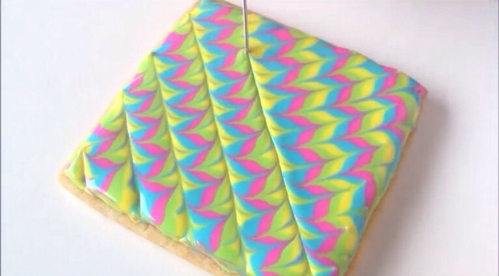 Turn your cookie 90 degrees and drag your toothpick through the second and the third piped arrow heads.