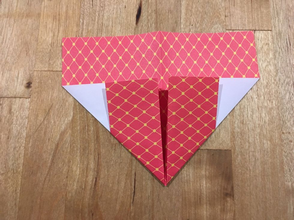 Turn your paper over. Fold 2 of the bottom corners to the center