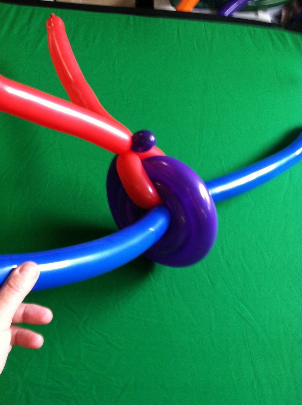 Twist a small bubble at the end of the spiral and attach around 2 of the spokes (trapping wheel between them)