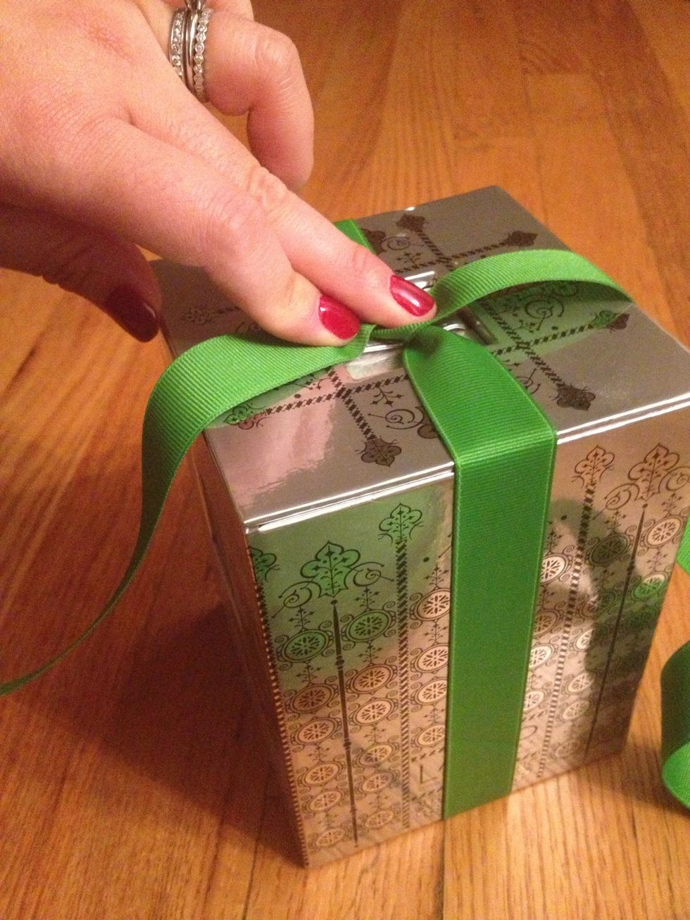 Twist the 2 ends of the ribbon 90 degrees so that they cross, creating an X on top.  Depending if you're left or right-handed, one end is over the front and the other is over the back of the box.