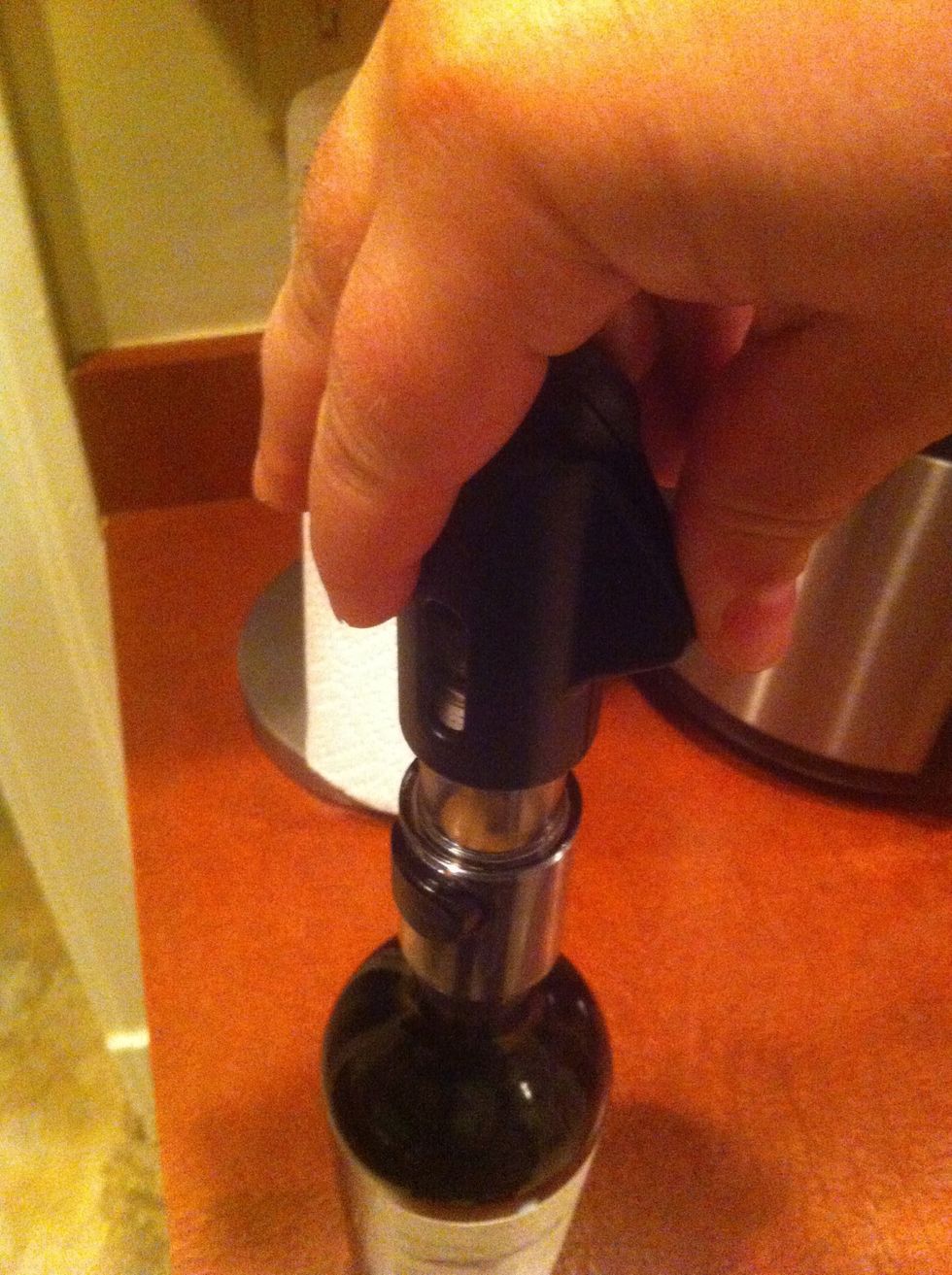 Twist the corkscrew into the center of the cork slowly by firmly, pulling it up into the clear plastic barrel until it is two thirds ejected, be mindful not to pierce the inside end of the cork.