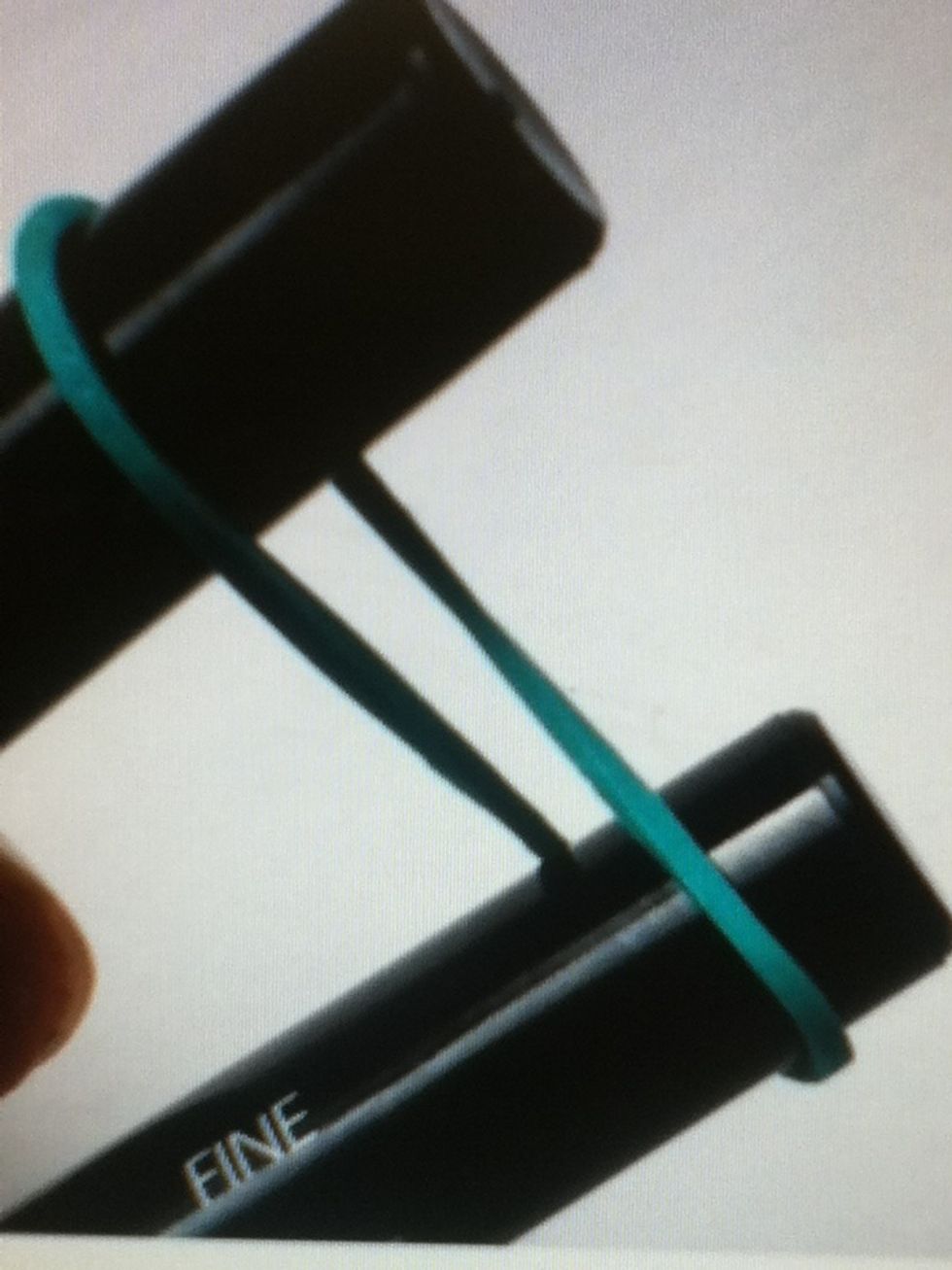 Twist the first elastic in a figure 8 on the pen.