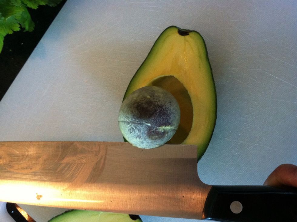 Twist the knife, pulling up and away from the avocado at the same time. The pit should come out easily of the avocado is ripe. Keep one of the pits for use later.