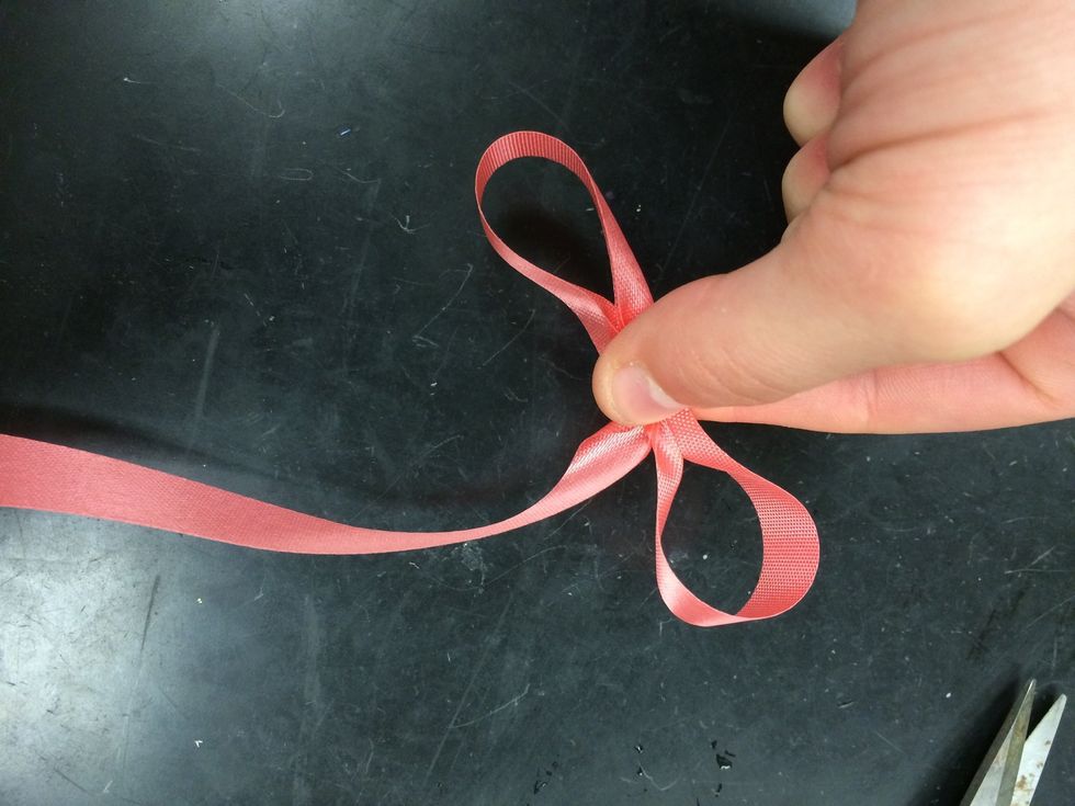 twist the ribbon and make another loop on the other side and pinch the middle of the ribbon together.
