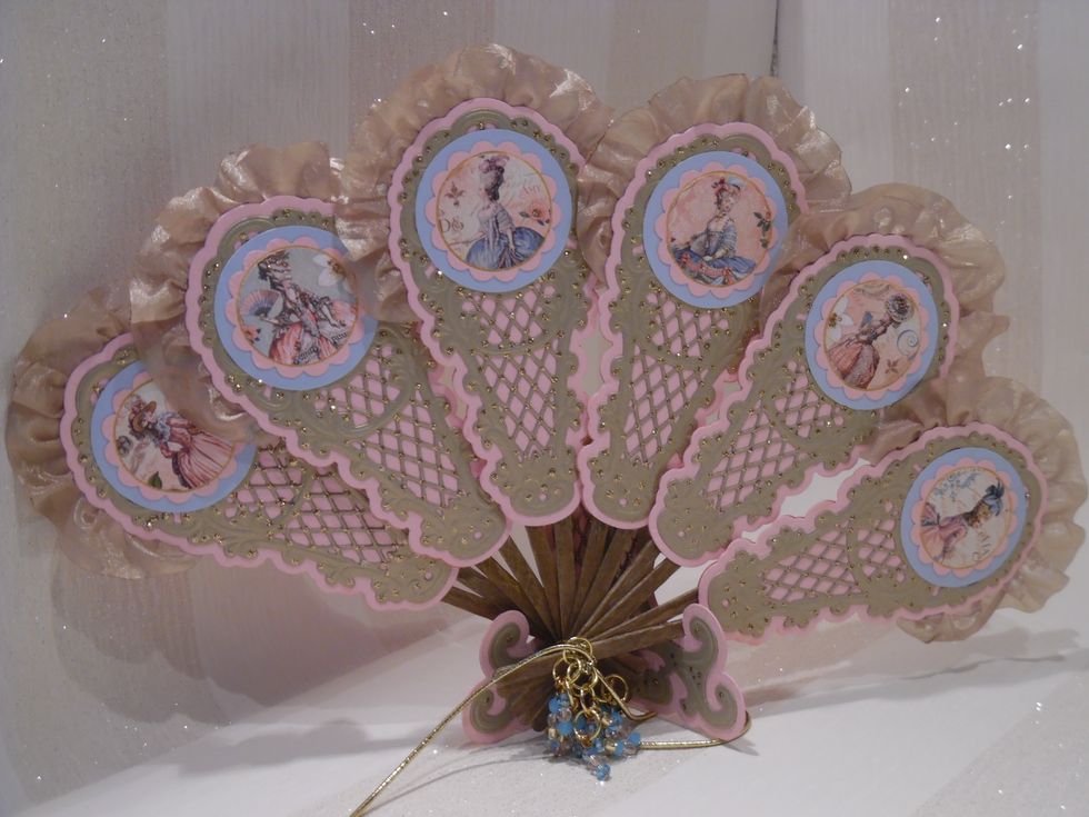 Two base panels cut from pink card using a Marianne fan die. Ornate latice top cut from antique gold card with Marianne die and attached to one pink panel. Add glitter dots with Stickles (to taste).
