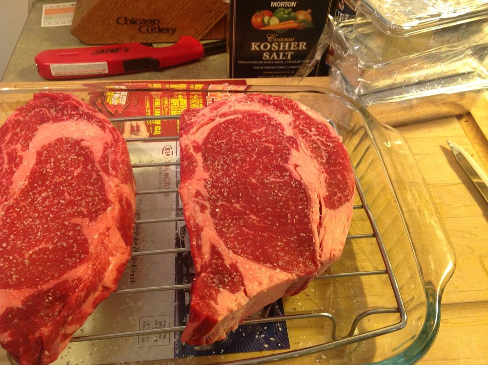 Two hours before grilling time, put steaks on a rack in a glass cake pan. Sprinkle both sides of steak generously with kosher salt and put in fridge. This is called dry brining.