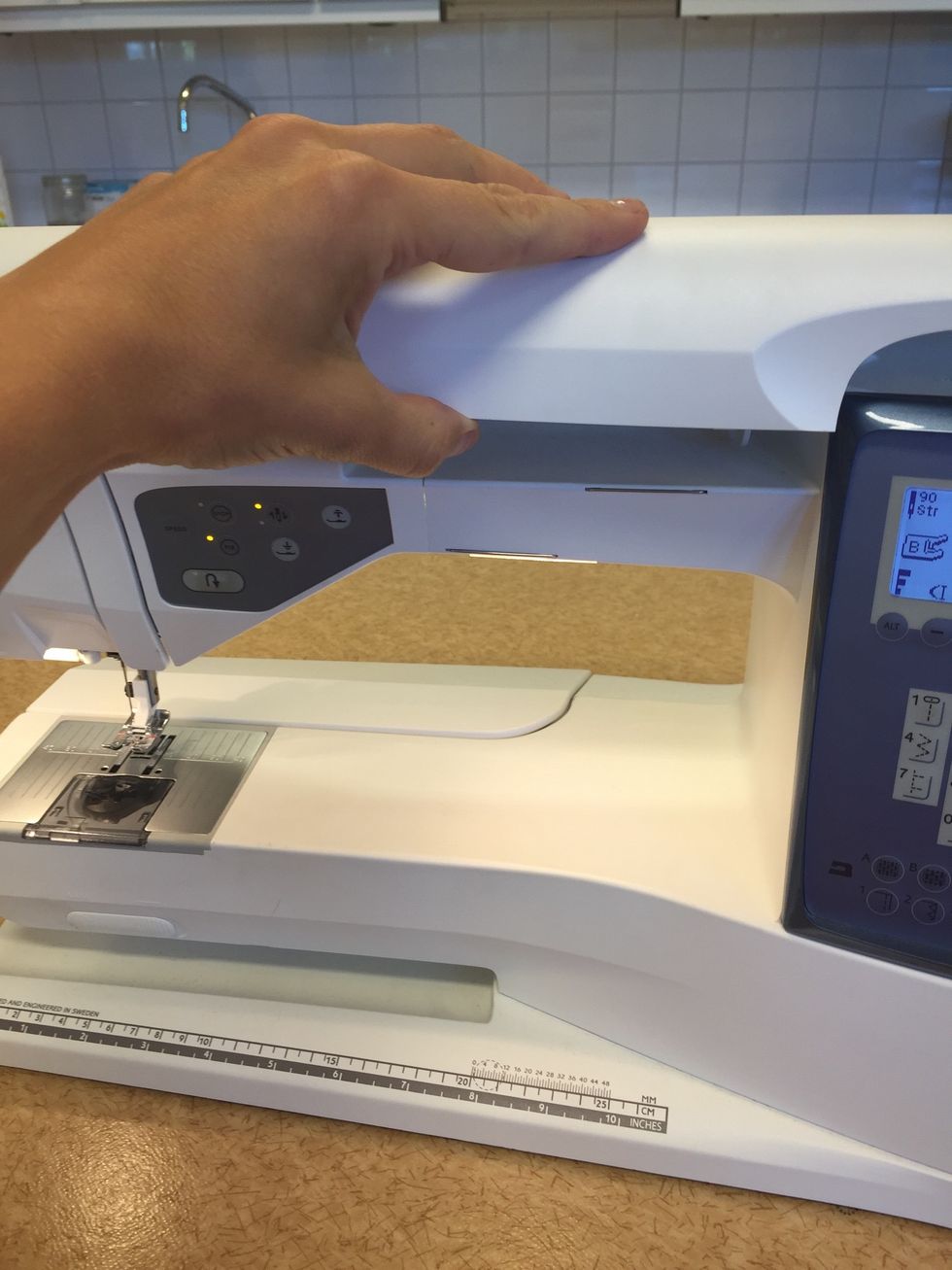 \u00d6ppna luckan p\u00e5 toppen av symaskinen.