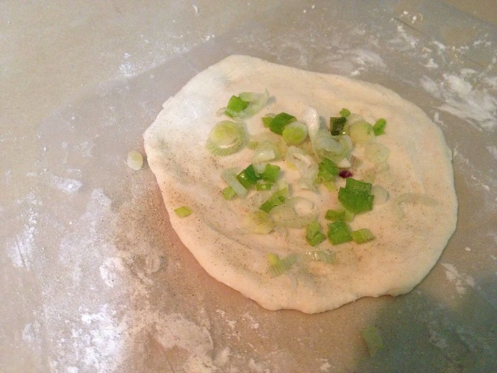 \u2022Next, divide the dough into small pieces/ ball. \u2022Roll into a flat round shape.  \u2022Spread the chopped scallion on the middle and roll it back.  *spread oil on your hands so the dough doesn't stick*