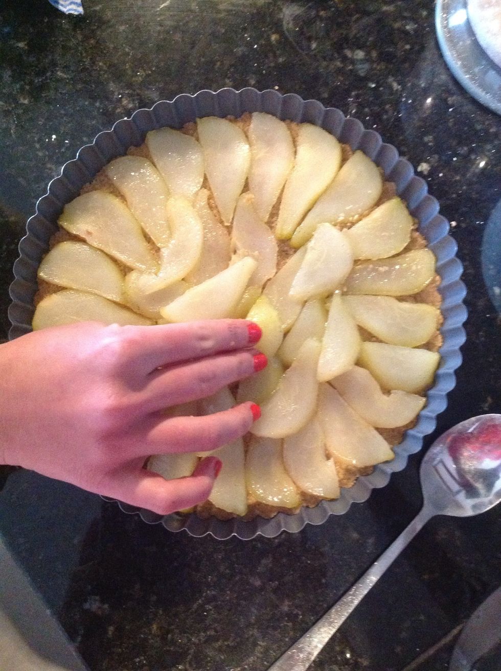 Una vez las peras est\u00e9n tiernitas, d\u00e9jalas enfriar un poco. C\u00f3rtalas en finas rebanadas y acom\u00f3dalas sobre la base de la tarta hasta cubrir todo.