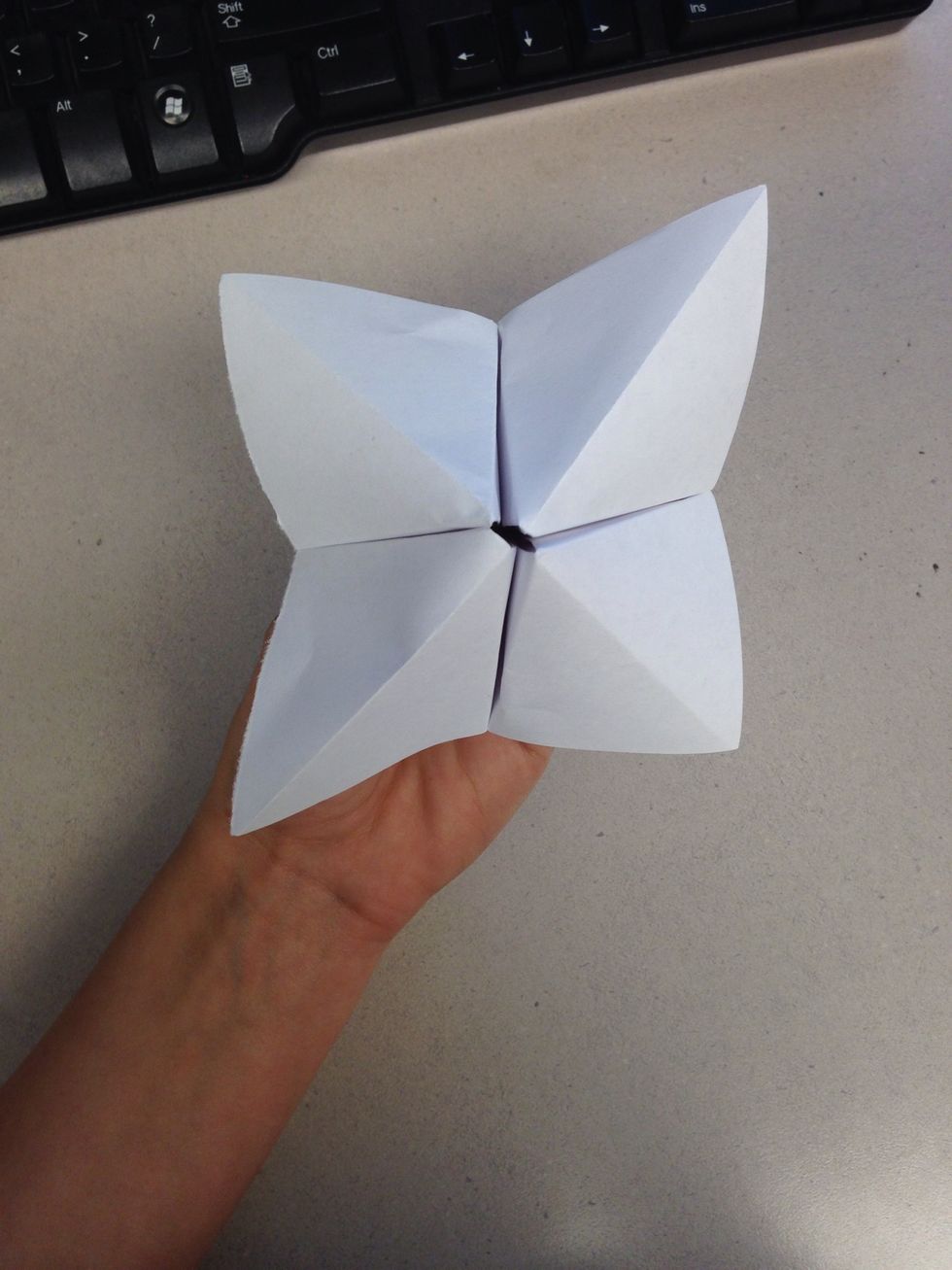 Unfold and pull the four ends together, making a diamond-like shape. Pick up each of the four square flaps, and put your fingers inside.