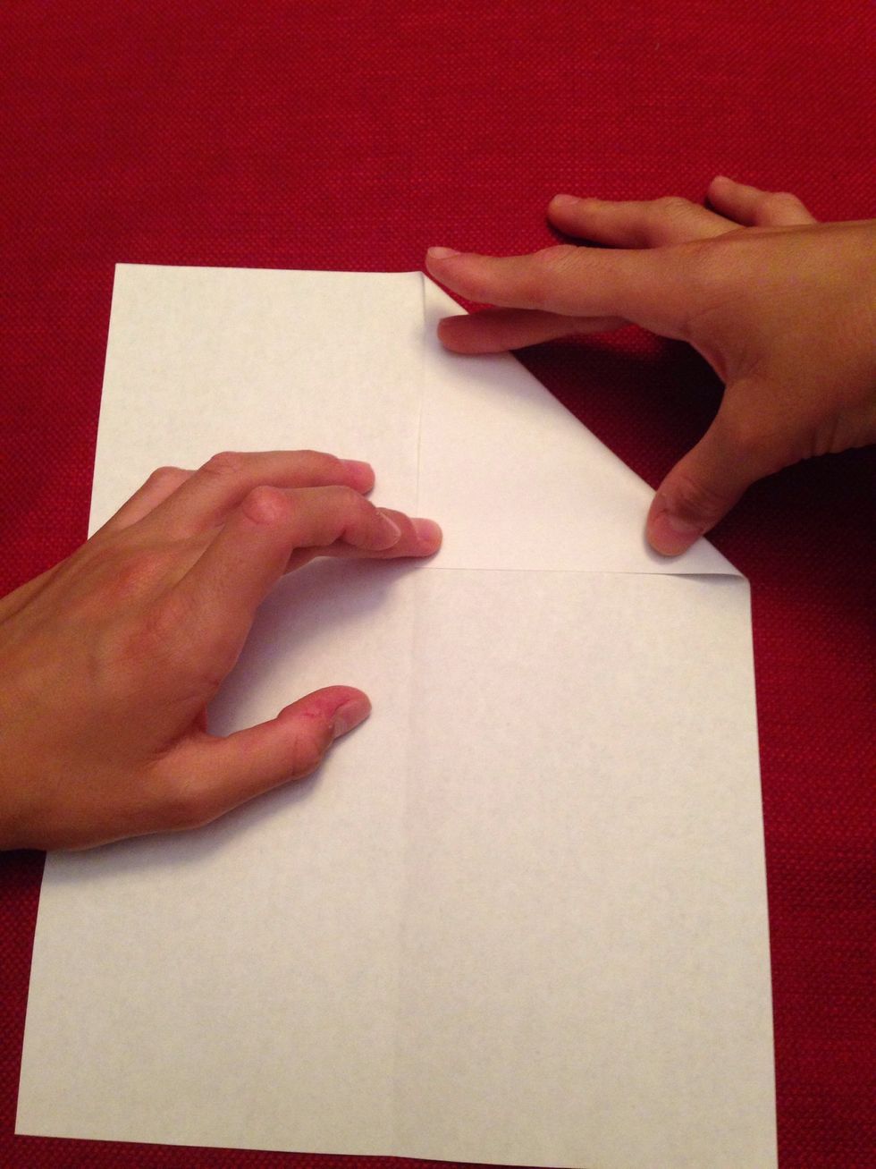 Unfold the paper and get a corner of the paper and fold it to the middle.