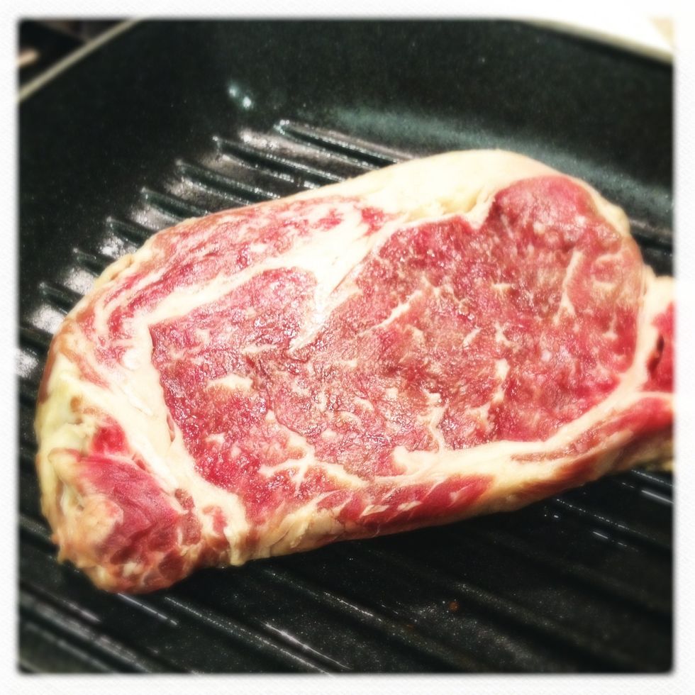 unpack the steak and set it at room temperature for about an hour or two.  use finger to press on the steak to make sure it's not cold.  pad and dry both sides of steak with paper towel