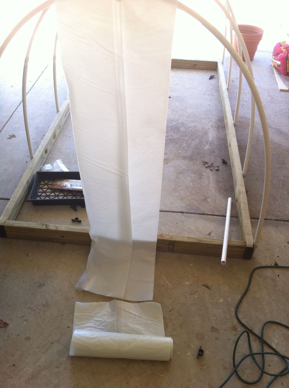 Unroll 1st fold of plastic sheet. Lay plastic from end to end of hoop house, dropping to ground on both ends. Extend 18" out from ground on both sides, then cut with scissors. Clip sheet to PVC pipe.