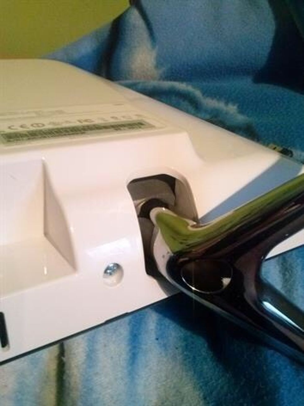 Unscrew the two legs and remove. There are 2 more screw that hold the white panel on, remove these. Along the bottom are two notches just big enough to get a flat head screwdriver in.