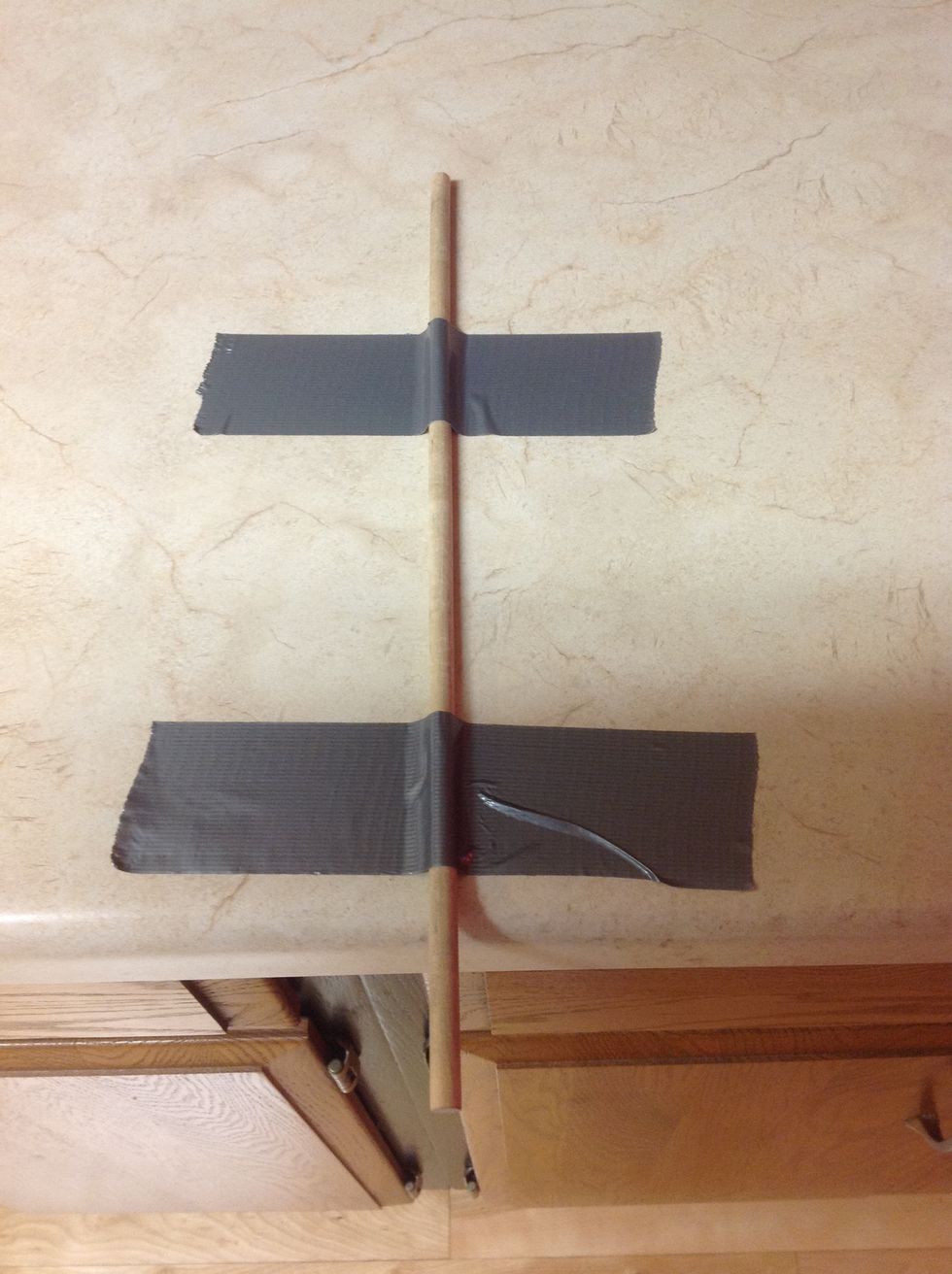 Use 2 pieces of duct tape to hold the dowel in place-one close to the edge of the desk and one toward the end of the dowel.