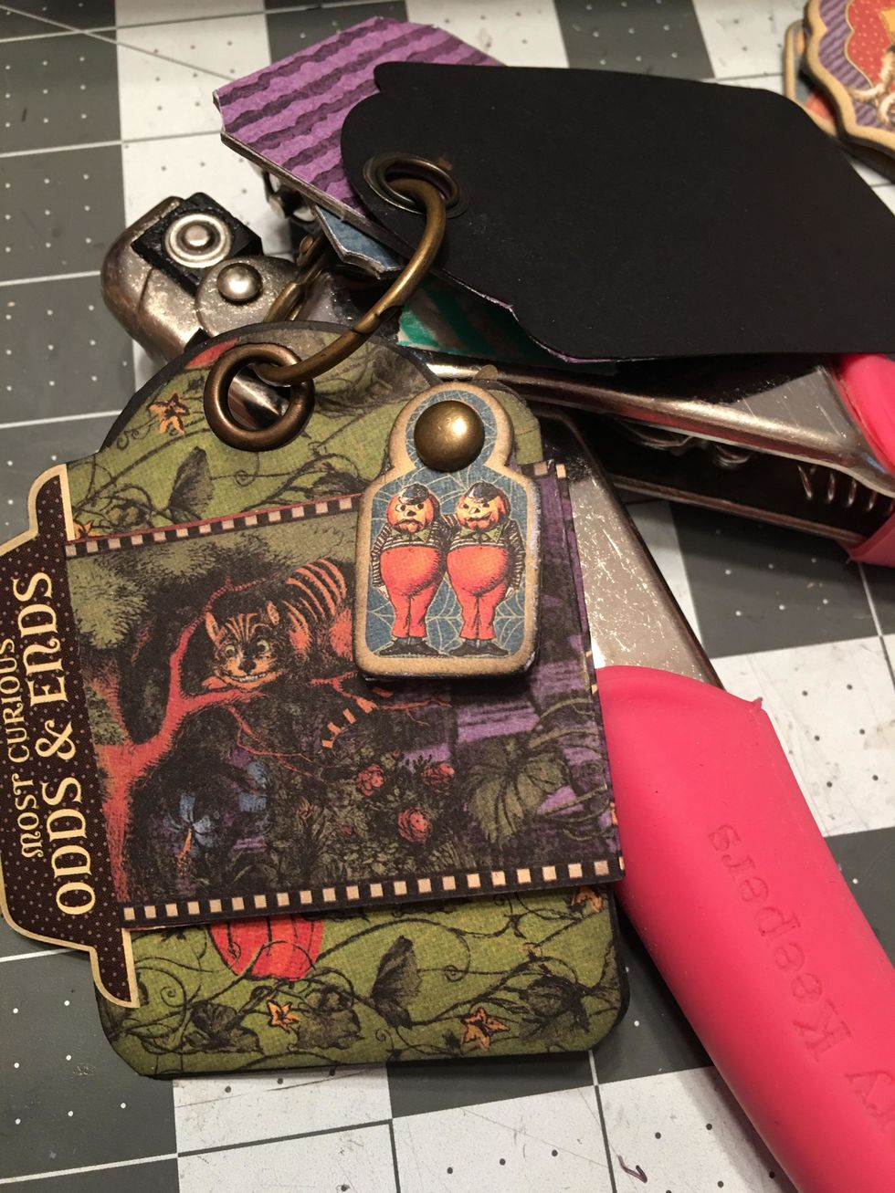 Use a brad and a small chipboard piece to create a swing closure for the fold out booklet on the tag page. It is best to add the brad BEFORE patterning the back side of the tag page.