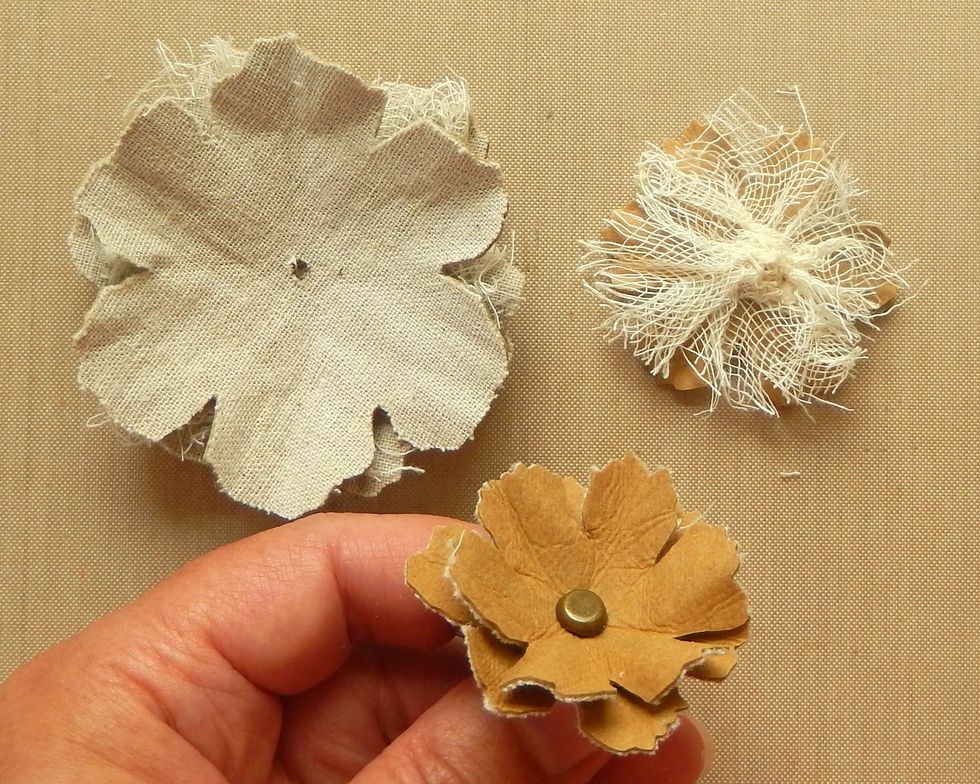 Use a brad to secure the layers of the flower together. Add the small fabric flowers upside down, the gauze covered small flower, the large fabric covered flower and the large gauze covered flower.