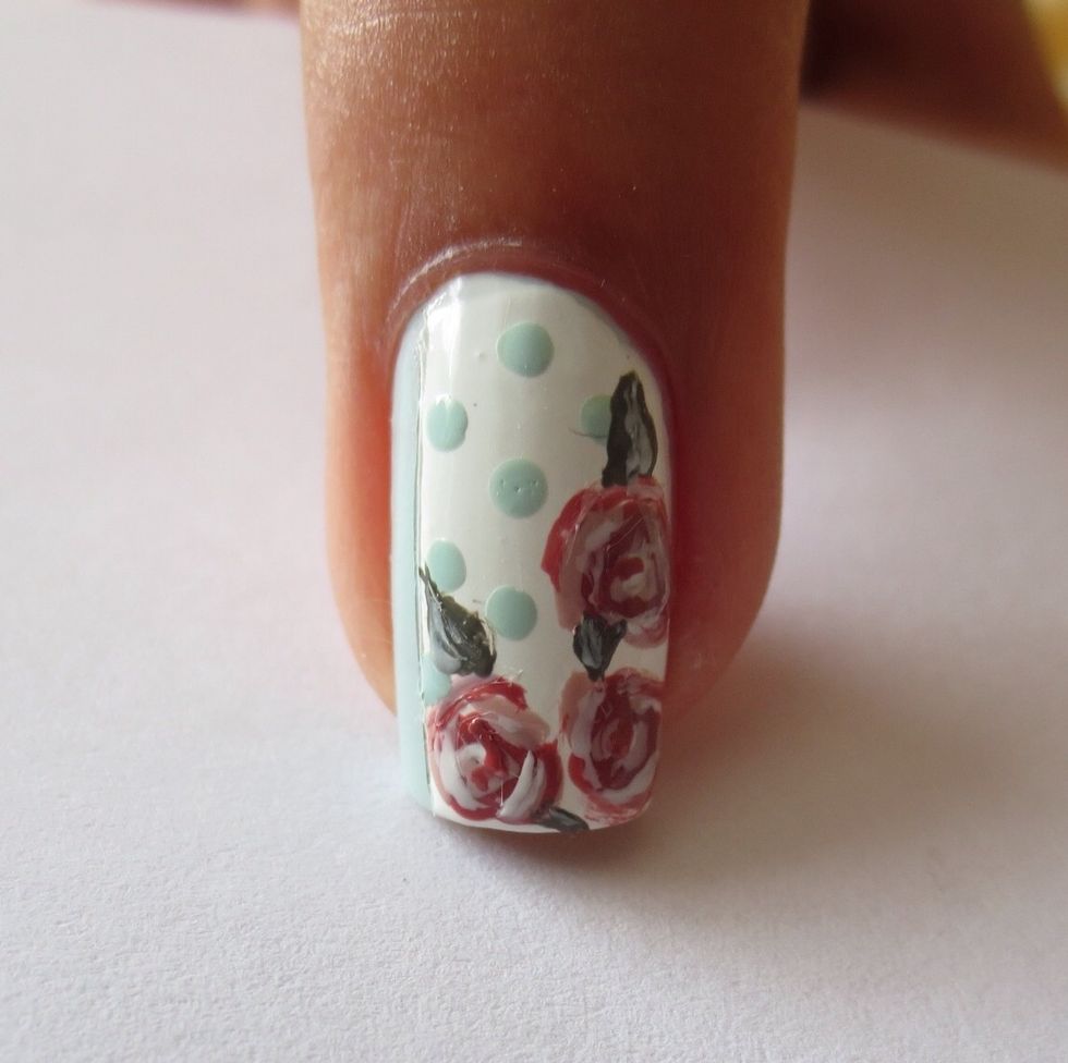 Use a brush and dark green polish to create small petals around the roses and add shadow with a small amount of white polish