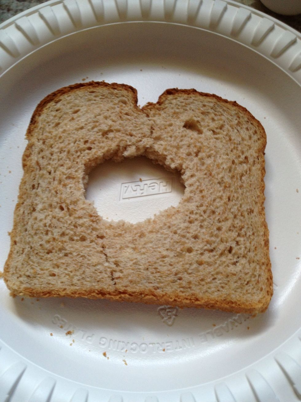 Use a cap, cup, or cookie cutter to punch a hole in the middle. If you don't have one available, just fold bread in half and bite a hole in the middle. Try to keep the bread from breaking into two.