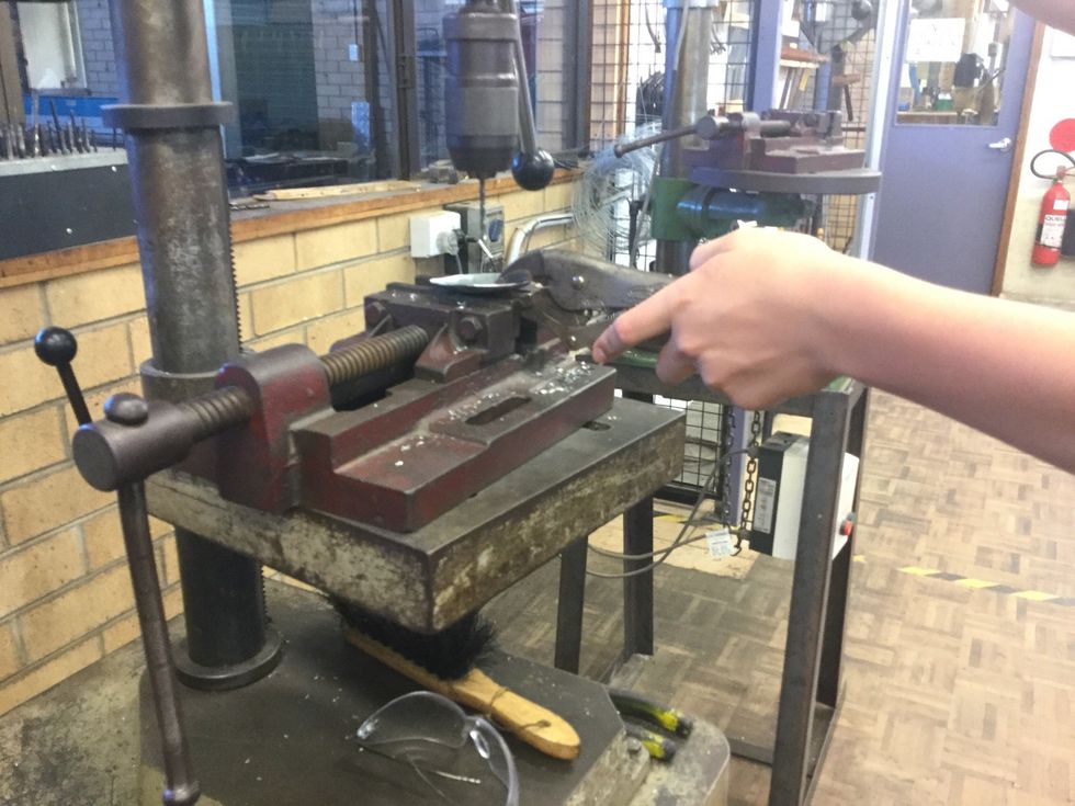 Use a clamp to hold your sheet metal and use the drill press the make a hole in the centre.