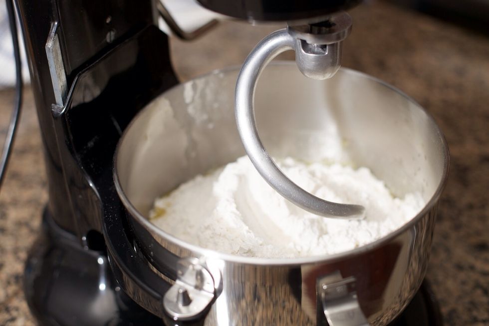 Use a dough hook if you have one available.  Turn the mixer on at the lowest setting.  If the dough doesn't form into a ball, add more flour \u00bc cup at a time.