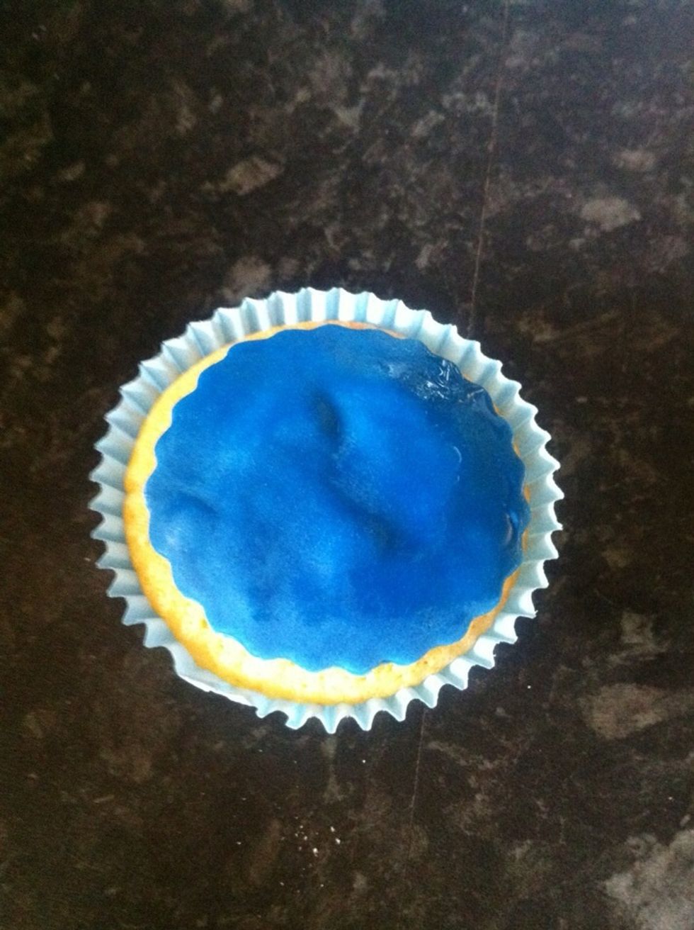 Use a drop of water to wash off the icing sugar. You can do this by dabbing your finger in some water and gently rubbing he water over the top. Use a little buttercream to stick the icing to the top